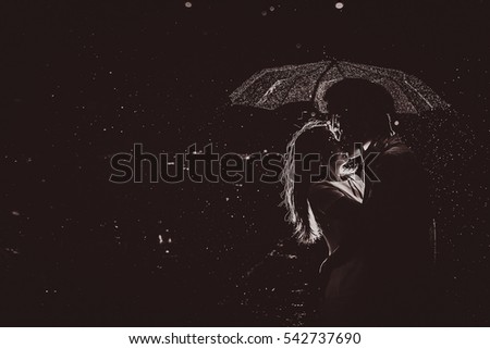 Dramatic photo of a bride and groom  in the night rain.