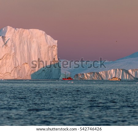 Tourists on the boat take pictures of the icebergs in the Disko Bay, Greenland. The source of these icebergs is the Jakobshavn glacier due to global warming and catastrophic thawing of ice