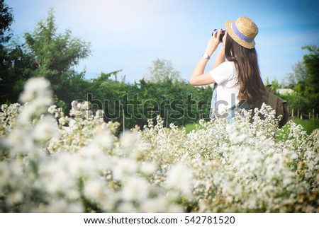 Asian hipster cute teen girl with camera in white flower garden, with vintage tone nature concept.