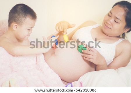 A happy family. Child play wooden block on belly of pregnant mother.