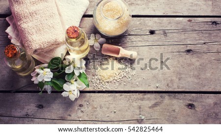  Sea salt, towels, aroma oil in bottles and flowers on  vintage  wooden background. Selective focus. Flat lay with copy space. Toned image. Royalty-Free Stock Photo #542825464