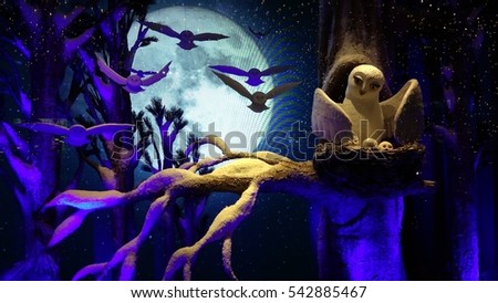 Christmas shop window scene taken in New York City, Manhattan. Picture shows owl and moon night scene with a touch of cold and frost. Owls are flying in the background and bare tree branches.