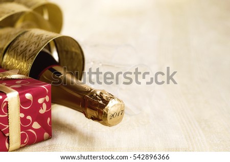 The bottle of champagne with gold glossy ribbon, flutes and red gift box. 2017 Happy New Year concept. Copy space Royalty-Free Stock Photo #542896366