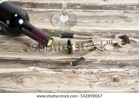 A bottle of red wine, a glass and a corkscrew