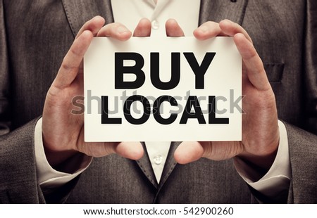 Buy Local. Businessman holding a card with a message text written on it