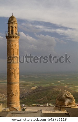 Minaret and the dome of the Great Mosque in Mardin, Turkey with the Mesopotamia plain and Syrian border on the background.