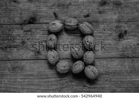 Black and white of top view of english alphabet made from walnuts on a wooden table. Letter Q