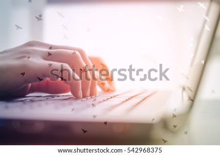 Technology computer social and freedom concept. Woman hand using keyboard and notebook double expose with birds fly. Shallow depth of field. Pastel tone filter effect color style. 