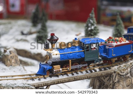 toy train with Santa Claus carries gifts through a snowy forest