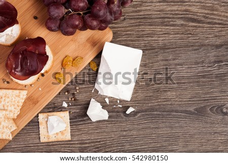 Grape, white cheese and crackers on wooden background. Healthy food