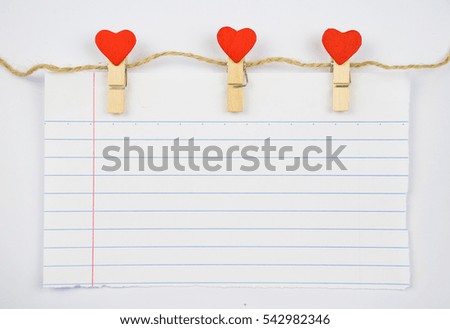 White notebook paper sheet hangs on the hearts clamps.