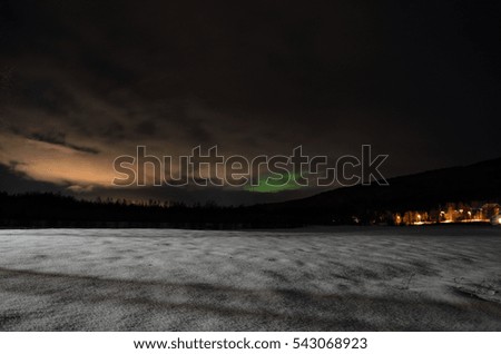 long white snowy field with green northern light in the background