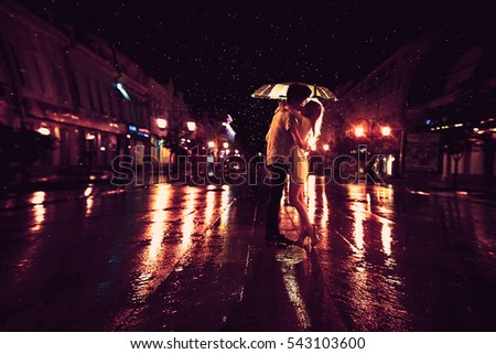 Love in the rain / Silhouette of kissing couple under umbrella