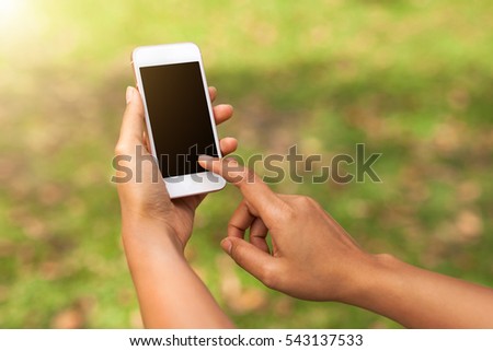 Woman hand hold and touch screen smart phone against spring green background