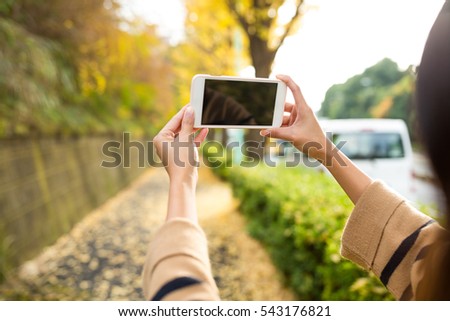 Woman using cellphone to take photo at park