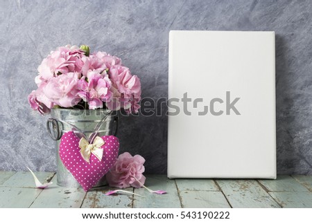 Pink carnation flower in zinc bucket and blank canvas frame on vintage wood