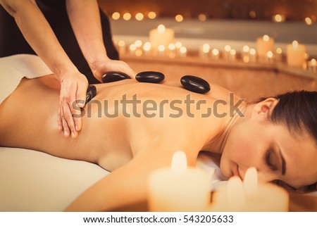 Professional beautician massaging female back by stones Royalty-Free Stock Photo #543205633