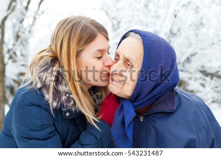 Picture of a young woman kissing her happy grandmother
