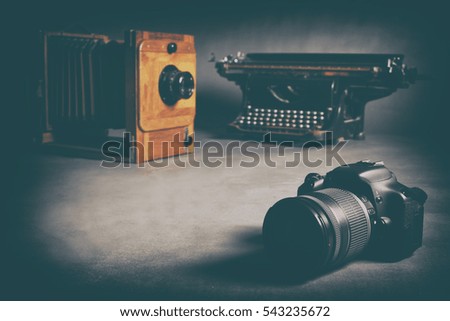 Antique Typewriter, old wooden camera and a modern SLR professional camera