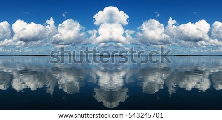 Multiple cumulus clouds in a bright blue sky with sea water reflections. Panoramic nature waterscape background image. Australia East Coast.



