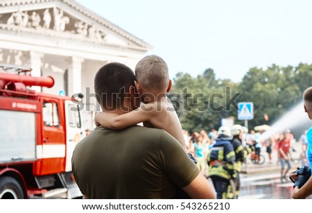 A father takes a little child boy to save him. Fire engine car on background. Father with his son in his arms. Protection concept.