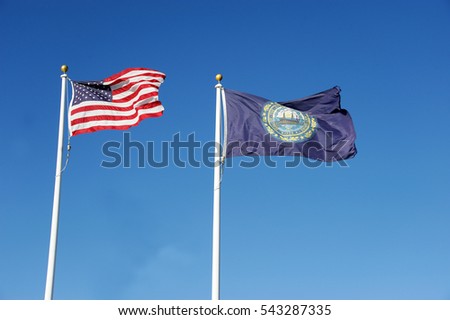 New Hampshire state flag and USA national flag waving under blue sky