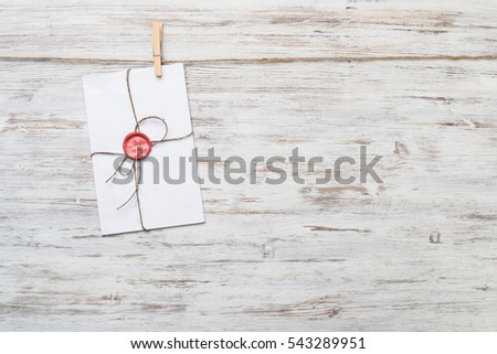 Envelope hanging on rope on wooden background