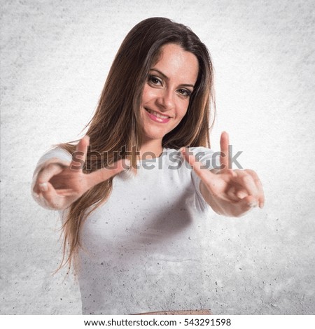 Young pretty girl making victory gesture on textured background