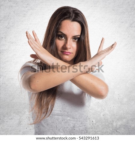 Young pretty girl making NO gesture on textured background