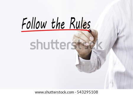 Businessman hand writing Follow the Rules with red marker on transparent wipe board, business concept