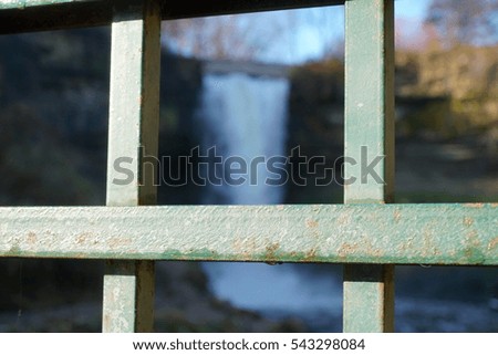 Beautiful winter waterfall photograph through steel fence - shallow depth of field focus. Minnehaha falls in Minneapolis Minnesota
