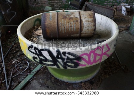 Old rusty oil drum sitting inside abandoned warehouse 