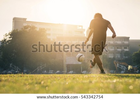 Man playing football at green field on morning. Royalty-Free Stock Photo #543342754