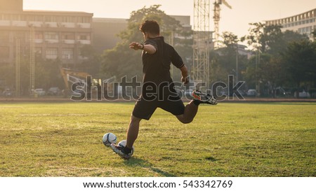 Man playing football at green field on morning. Royalty-Free Stock Photo #543342769