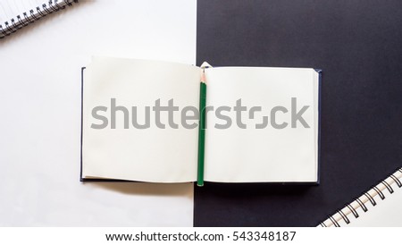 Modern white and black office desk table with notebook and pencil on black and white background.Top view with copy space, flat lay.