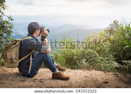 Young professional traveler man with camera shooting outdoor, fantastic mountain landscape.