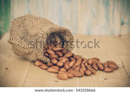 Almonds in brown bowl on textured wooden background