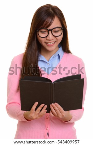 Young happy Asian teenage girl smiling and reading book isolated against white background