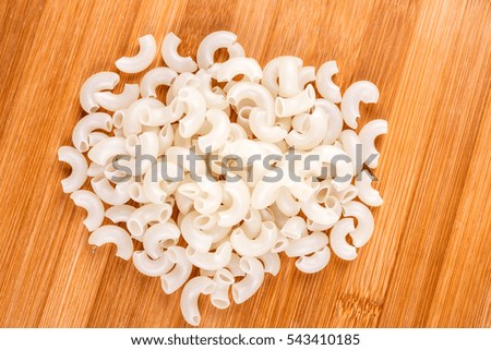 White rice elbow macaroni isolated on a wood background