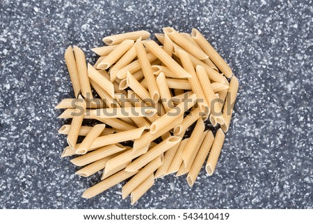 Brown rice penne on a mottled grey blue background