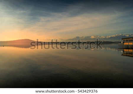 Sunset on lake, with mountains and snow on background