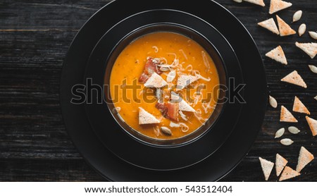 Cream of pumpkin soup. dark background. natural light.