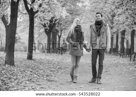 Full length of couple walking while looking up in park during autumn
