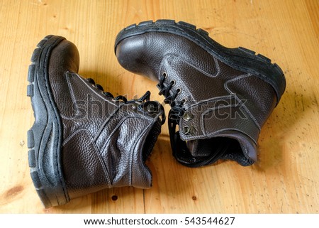 a pair of black safety shoes on wooden background