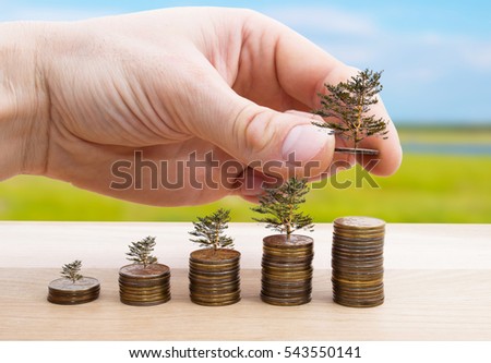 Male hand putting money coin with tree stack growing business