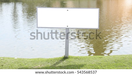 Empty billboard for your advertise on grass by a lake