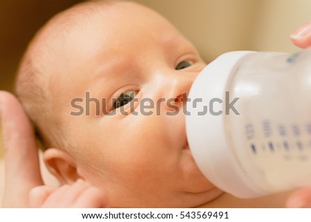 Cute newborn baby drinking milk from a bottle. Stock photo