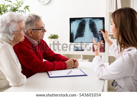 Doctor shows results to old patient x-ray of the lungs, smoking cigarettes problem Royalty-Free Stock Photo #543601054