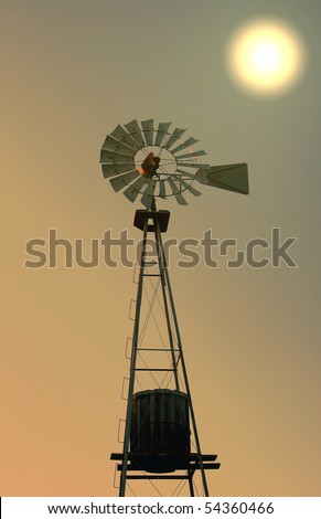 silhouette of old fashioned windmill water tower at sunset