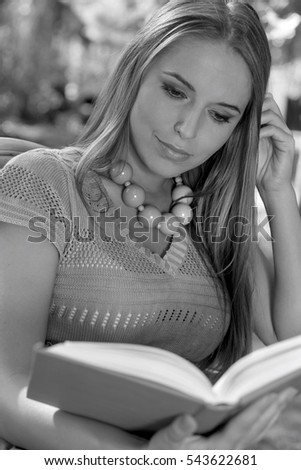 Young woman with long hair reading book in park